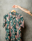 Hanging casual teal shirt adorned with artistic floral designs for a fresh summer look