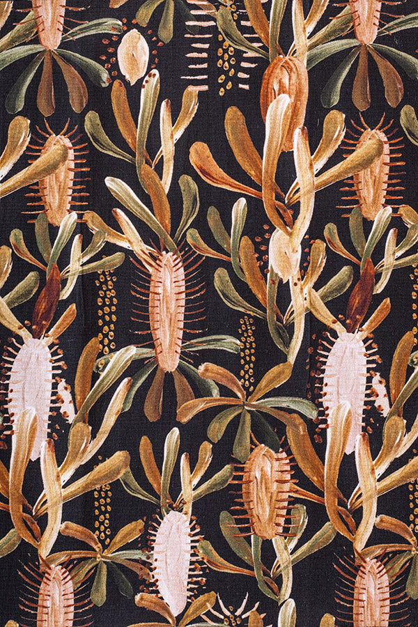 Distinctive black background with a print inspired by resilient grass trees, highlighted with accents in burnt orange, sage green, and light pink, reflecting their growth after wildfires